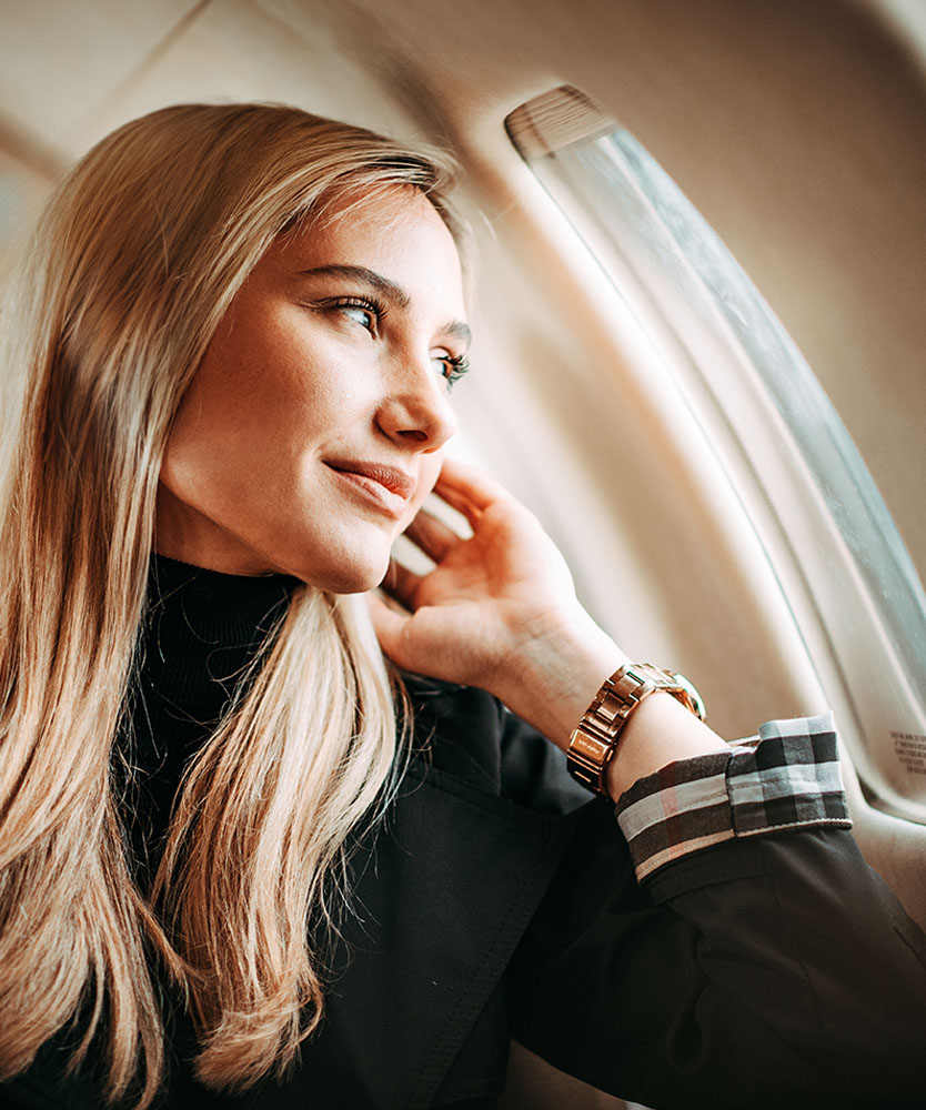 Blonde woman in black suit looking out window of airplane - Out of Town Patient resources in Ohio